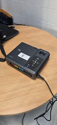 two laptops sitting on a table with a cord attached to it