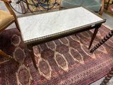 une table au plateau en marbre posée sur un tapis dans une pièce