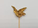 a gold bird on a stick on a white surface
