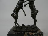 a statue of two deer fighting each other on a marble base