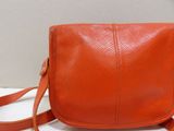 a close up of an orange purse on a white surface