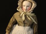 a doll of a woman in a white dress and bonnet