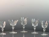 six wine glasses sitting on a glass shelf on a table
