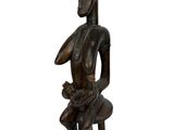 une image représentant une statue en bois d'une femme assise sur une chaise
