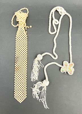 un collier de perles blanches et une cravate blanche posés sur une table