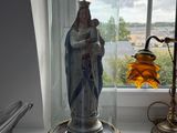 une statue représentant une femme, placée sous un dôme de verre sur le rebord d'une fenêtre
