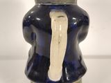 a blue vase with a white handle on a white table