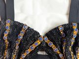 a close up of a black bralet with gold and blue beads