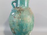 a green vase with a handle on a white table