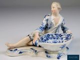 une figurine représentant une femme assise sur un bol