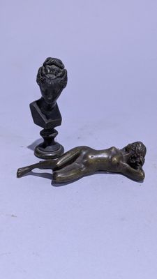 statue en bronze représentant une femme allongée sur le dos à côté d'un buste d'homme