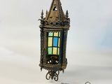an old brass lantern with a stained glass window on a chain