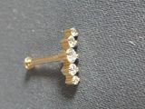 a close up of a gold nose piercing with three diamonds