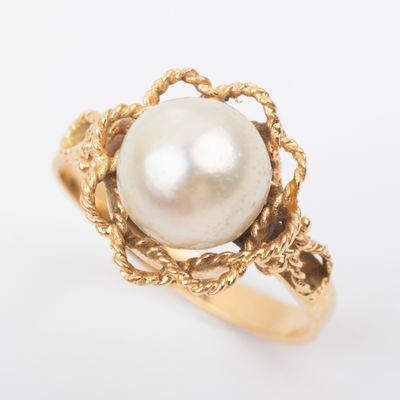 a close up of a gold ring with a pearl in the center