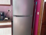 a refrigerator in the corner of a kitchen with a pink wall