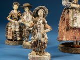 three figurines of women dressed in traditional clothing are posed on a blue surface