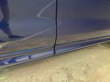a close up of a car door with a person walking in the background