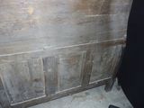 a wooden cabinet with a door and a black chair in front of it