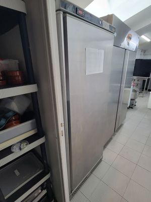 un réfrigérateur argenté dans une cuisine dotée de nombreuses étagères