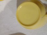une tasse et une soucoupe jaunes posées sur une table blanche