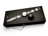 a watch sitting on top of a black box on a white surface