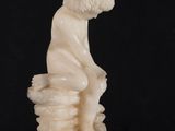 statue of a dog sitting on a rock on a black background