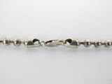 a close up of a chain of silver beads on a white surface