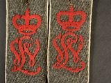 pair of british army officer ' s collar badges with red thread