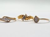 trois bagues en or serties de diamants, posées sur un fond blanc
