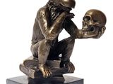 statue en bronze représentant un singe tenant un crâne posé sur un livre