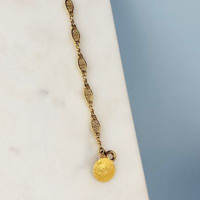 un gros plan d'un collier plaqué or orné d'une pièce de monnaie