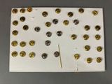 a clock made out of gold and silver buttons on a white board