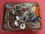 un plateau en bois rempli de bijoux variés, posé sur un fond rouge