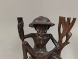 statue of a man sitting on a rock with a stick and a hat