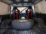two seats in the back of a truck with a tire in the bed