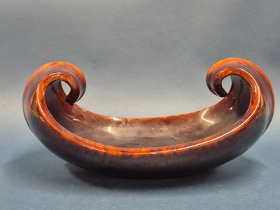 a brown bowl with a curved handle on a table