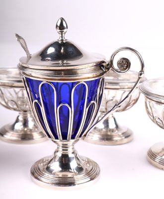 trois verres argentés et bleus avec des cuillères, posés sur un support blanc