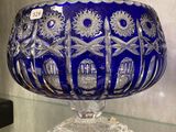 un grand saladier en verre bleu posé sur une table en verre