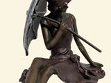 a bronze statue of a woman sitting on a rock holding an umbrella