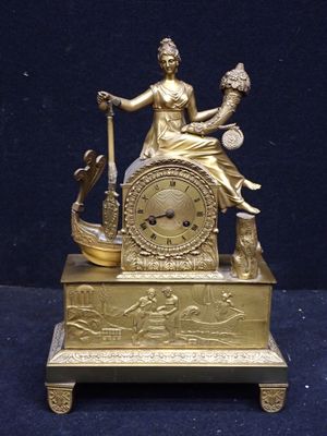 une horloge en or avec une femme assise dessus