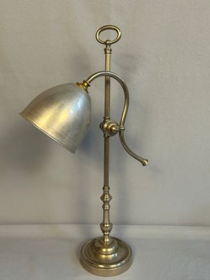 une lampe de table ancienne en laiton avec un abat-jour en métal, sur fond blanc