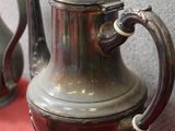 trois théières en argent posées sur une table rouge