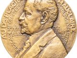 a close up of a gold medal with a man in a suit and tie