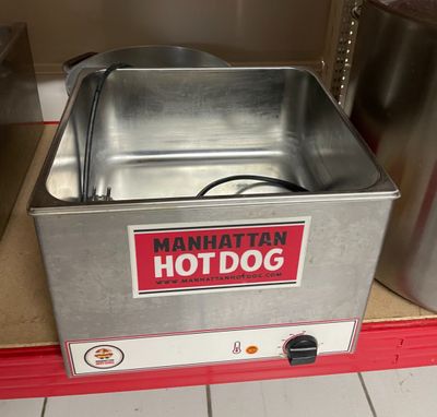 un hot-dog posé dans un récipient en métal sur le comptoir