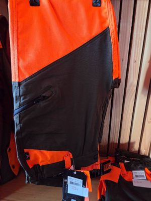 orange and black backpacks are lined up against a wooden wall