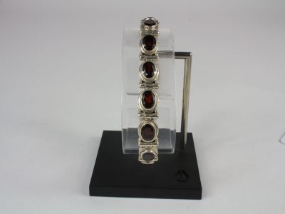 silver bracelet with garnets on display on a black stand