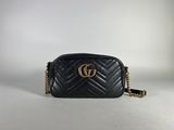 a black gucci bag with a gold gg logo on the front