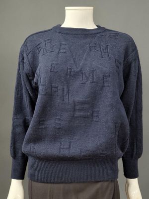 un mannequin portant un pull bleu avec des lettres dessus