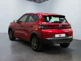 the red car is parked in a large room with a white wall