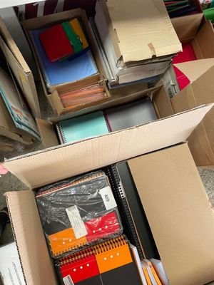 une boîte remplie de livres posée par terre à côté d'une pile d'autres livres
